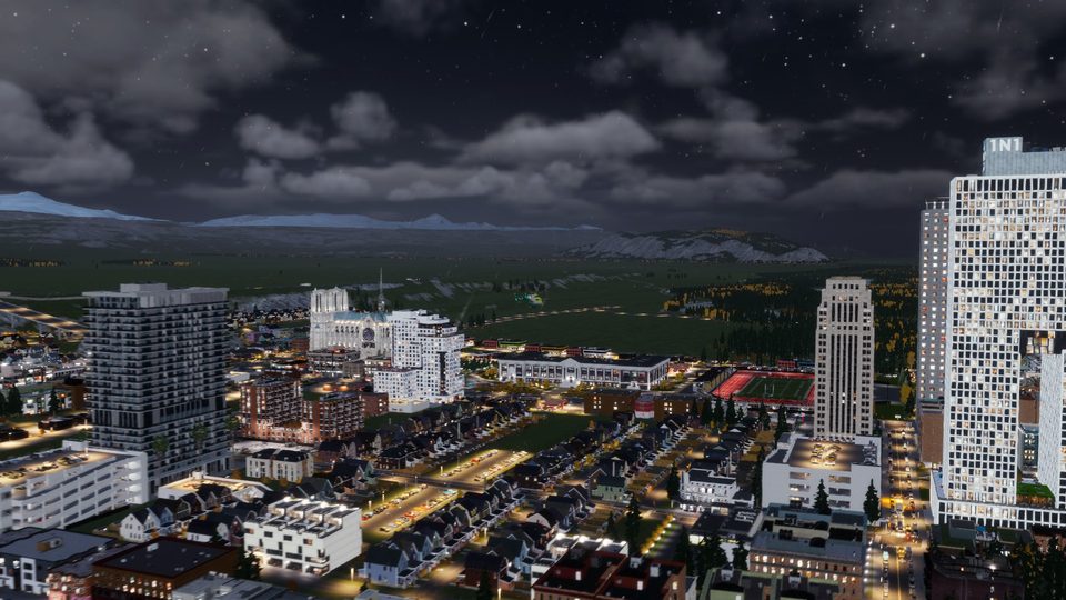 Night view of downtown towers with a school athletics field visible among the neighborhood